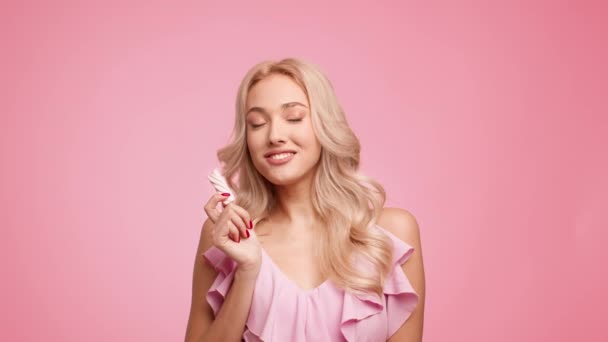 Γοητευτική ξανθιά κυρία τρώει νόστιμο Marshmallow Posing πάνω από ροζ φόντο — Αρχείο Βίντεο