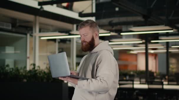 Barbu Guy à l'aide d'un ordinateur portable de travail en ligne debout au bureau — Video
