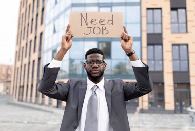 İş konseptine ihtiyacım var. Afro-amerikan ofis çalışanı ofisin yakınında otururken posterini tutuyor.