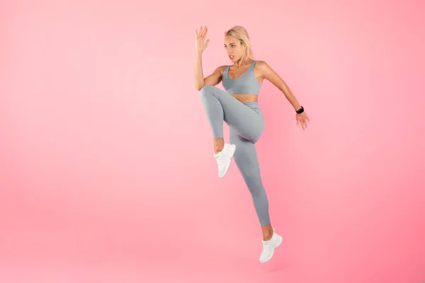 Νεαρή γυναίκα άλμα και άσκηση απομονώνονται σε ροζ φόντο — Φωτογραφία Αρχείου