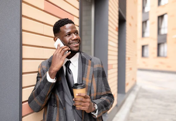 Afroamerikansk affärsman eller manager talar på mobiltelefon under pausen, promenader i staden och dricka kaffe — Stockfoto
