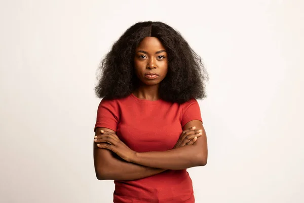 严肃而年轻的非洲裔美国妇女的画像，她双手交叉地站着 — 图库照片