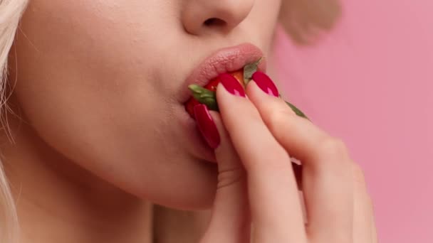 Unrecognizable Blonde Woman Eating Strawberry Over Pink Studio Background, Closeup — Stock Video