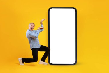 Turuncu arka planı boş ekranlı, cep telefonunun yanında dans eden komik, olgun bir adam. Mobil müzik uygulaması için model.