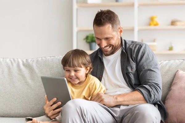 Fiatal apa és kisfia video chat keresztül digitális tabletta, ül a kanapén, és mosolyogva modul, üres hely — Stock Fotó