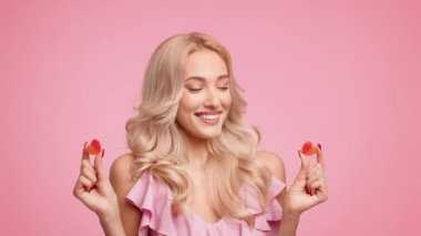 Gülümseyen Sarışın Kadın İki Kalp Şekeri Tutuyor, Pembe Arkaplan