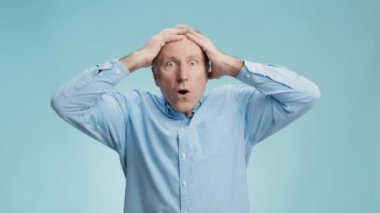 Şaşırmış yaşlı, gri saçlı bir adamın stüdyo portresi. Şok ve inançsızlık içinde kafasını tutuyor.