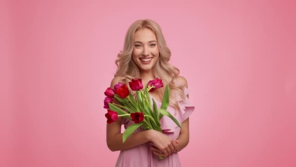 Blondýny dáma drží tulipány kytice slaví dámské den, růžové pozadí — Stock video