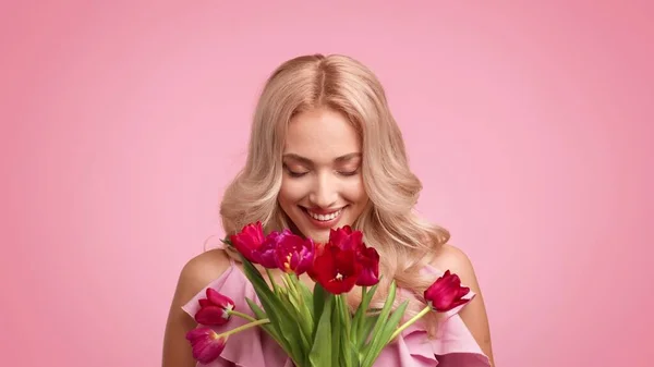 Feliz rubia hembra celebración ramo de tulipanes sobre fondo rosa — Foto de Stock