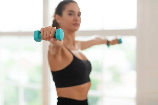 Sportliche junge Frau trainiert mit zwei Kurzhanteln — Stockfoto