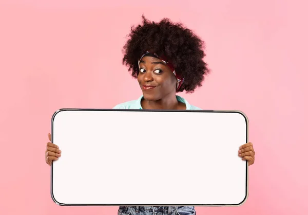 Wesoły czarny lady pokazując duży biały pusty ekran smartfona — Zdjęcie stockowe