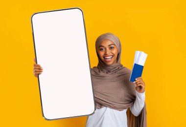 Neşeli bayan büyük boş akıllı telefon ekranı ve biletleri gösteriyor.