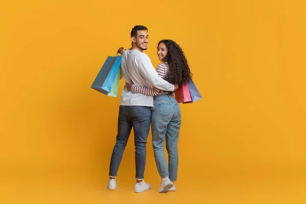 Compras em família. Cônjuges árabes felizes abraçando e segurando sacos coloridos Shopper — Fotografia de Stock