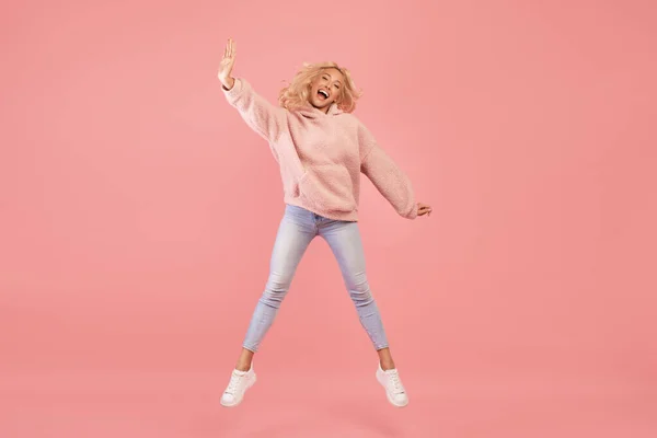 Uttrycka glädje och lycka. Full längd skott av aktiv ung kvinna hoppa och ha kul över rosa bakgrund — Stockfoto