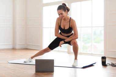 Genç siyahi kadın dizüstü bilgisayarla mindere atlıyor.