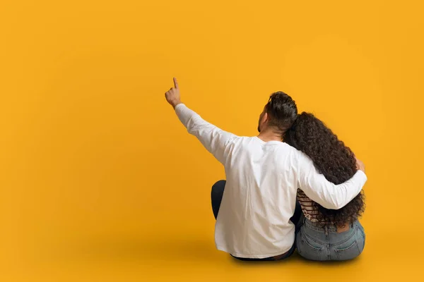 Homem e mulher abraçando fundo amarelo e apontando para espaço de cópia — Fotografia de Stock