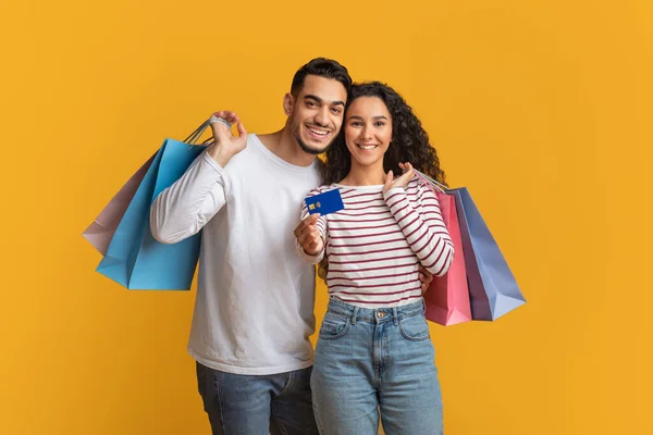 Compras fáceis. Feliz Oriente Médio Casal Segurando Cartão de Crédito E Sacos De Comprador — Fotografia de Stock