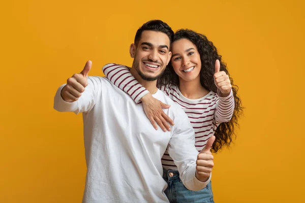 Wir empfehlen. Fröhliche junge arabische Ehepartner zeigen vor der Kamera Daumen nach oben — Stockfoto