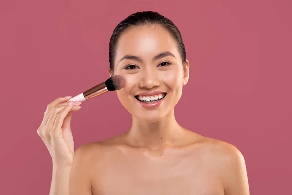 Fröhlich koreanische Frau mit Make-up Pinsel lächelt in die Kamera — Stockfoto