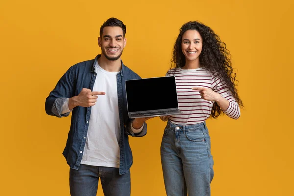 Web sitesi modeli. Siyah ekranlı dizüstü bilgisayarı gösteren mutlu, genç bir Arap çift. — Stok fotoğraf