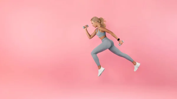 Young Woman Running With Dumbbells Isolated On Studio Background — Stock Photo, Image