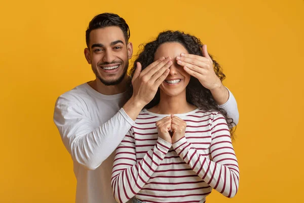 Alegre árabe chico jugando adivina quién con su novia, cubriendo sus ojos — Foto de Stock