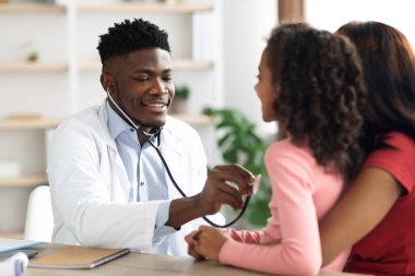 Zenci doktor, steteskopla çocuğun nefesini dinliyor.