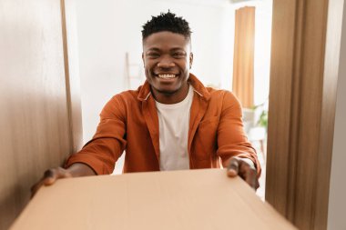 Siyah adam pizza kutusunu tutuyor. Açık Kapıda duruyor.