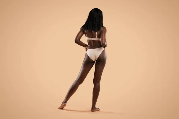 Back view of black lady posing in underwear on beige — Stock Photo, Image