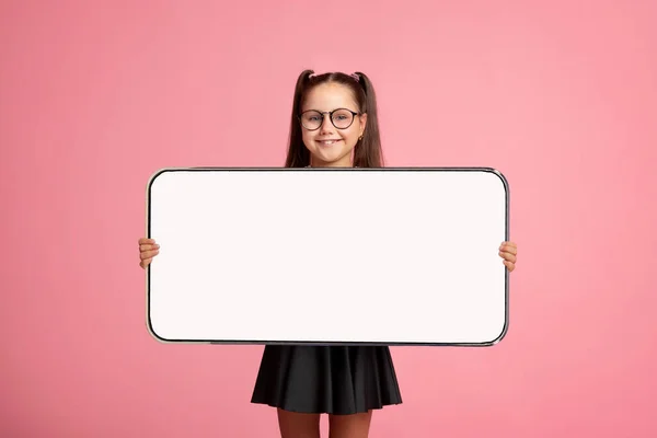 Klein schoolmeisje tonen witte lege smartphone scherm — Stockfoto