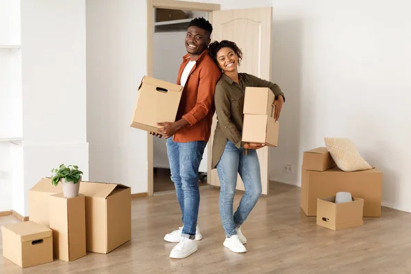 Χαρούμενο μαύρο ζευγάρι κρατώντας κινούμενα κουτιά στο νέο τους σπίτι — Φωτογραφία Αρχείου