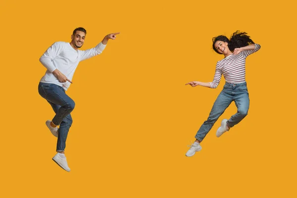 大宣伝だ。ケアフリー若いアラブカップルジャンプし、中でポインティング — ストック写真