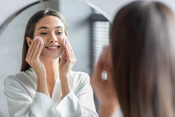 Hautpflege-Routine. Attraktive junge Frau reinigt die Haut mit Baumwollpolstern in Spiegelnähe — Stockfoto