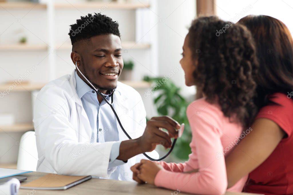 Black man doctor listening to child patient breath with stethoscope