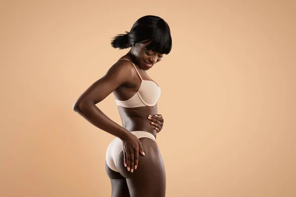 Sonriente mujer afroamericana delgada en ropa interior tocando sus nalgas — Foto de Stock