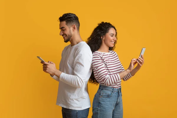 Gadget Kecanduan. Pasangan Arab Muda Memegang Smartphone Dan Berdiri Kembali Ke Kembali — Stok Foto