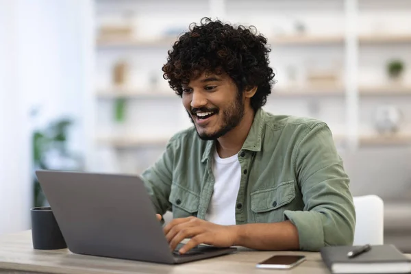 Szczęśliwy, ciemnoskóry młody człowiek korzystający z nowoczesnego laptopa — Zdjęcie stockowe