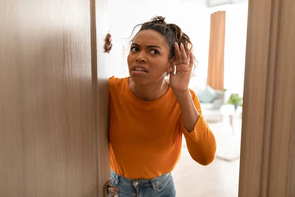 Mécontent noir dame écoute debout dans ouvert porte à la maison — Photo