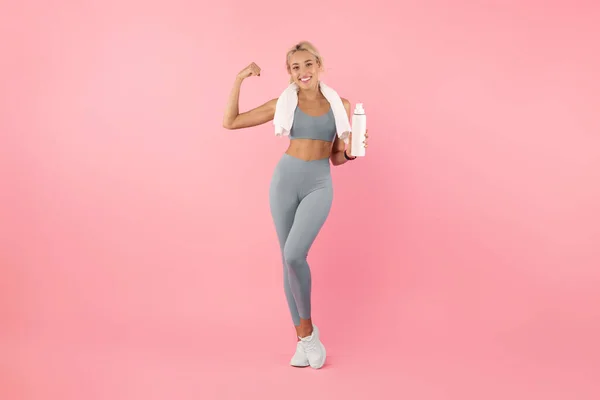 Desportivo sorrindo mulher posando no estúdio com garrafa de água — Fotografia de Stock