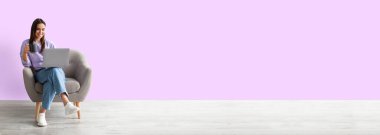 İnternette çalışan bir kadın, elinde kahveyle koltukta oturuyor, dizüstü bilgisayar kullanıyor.