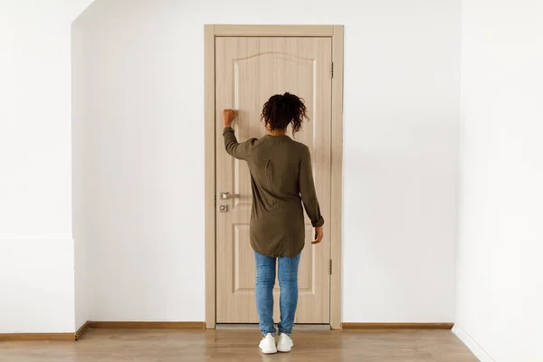 Mulher afro-americana irreconhecível batendo na porta interior, vista traseira — Fotografia de Stock