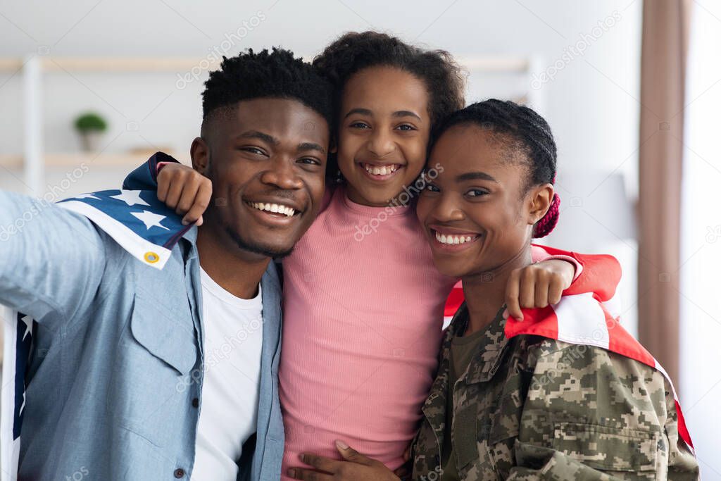 Positive black family posing with flag of the US