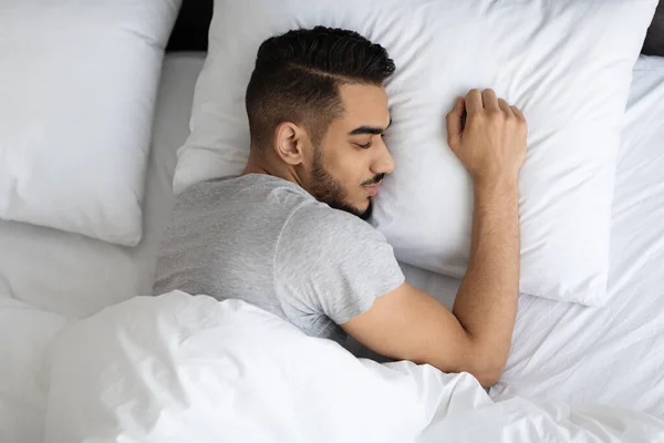 Fiatal arab férfi alszik kényelmes ágyban otthon, felső nézet — Stock Fotó