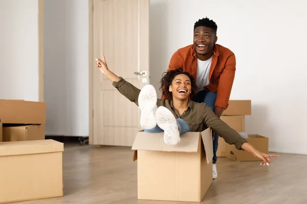 Szczęśliwy afrykański mężczyzna jazda kobieta w Moving Box w domu — Zdjęcie stockowe