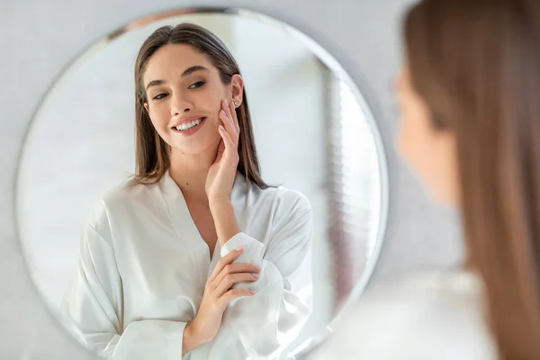 Zelfzorg concept. Portret van aantrekkelijke jonge vrouw op zoek naar spiegel — Stockfoto