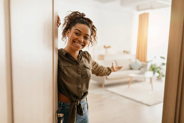 Glückliche schwarze Frau öffnet Tür zeigt Wohnzimmer zu Hause — Stockfoto