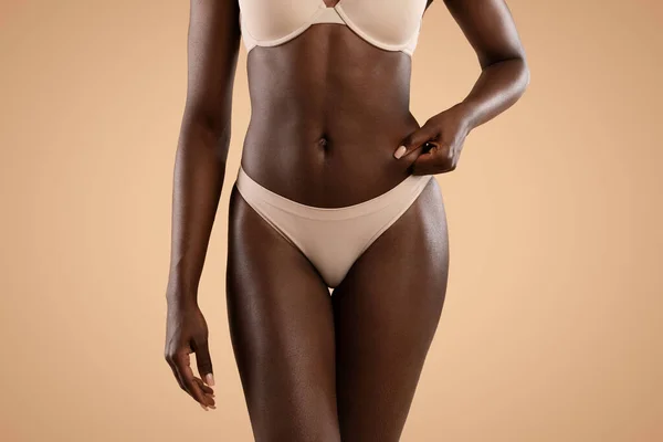 Невизначена чорна жінка в нижній білизні показує надмірний жир на животі — стокове фото
