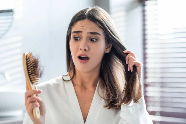 Shocked hembra cepillado cabello en cuarto de baño y preocupado por la pérdida de cabello — Foto de Stock