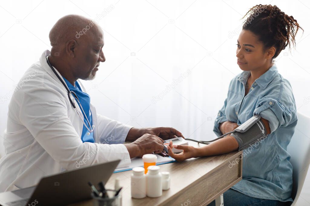 Black doctor checking measuring pressure on pregnant patients hand pulse