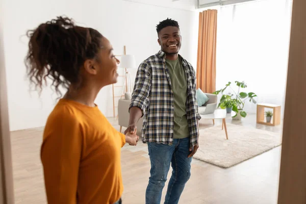 Pareja negra entrando en su casa sosteniendo las manos de pie en el interior — Foto de Stock